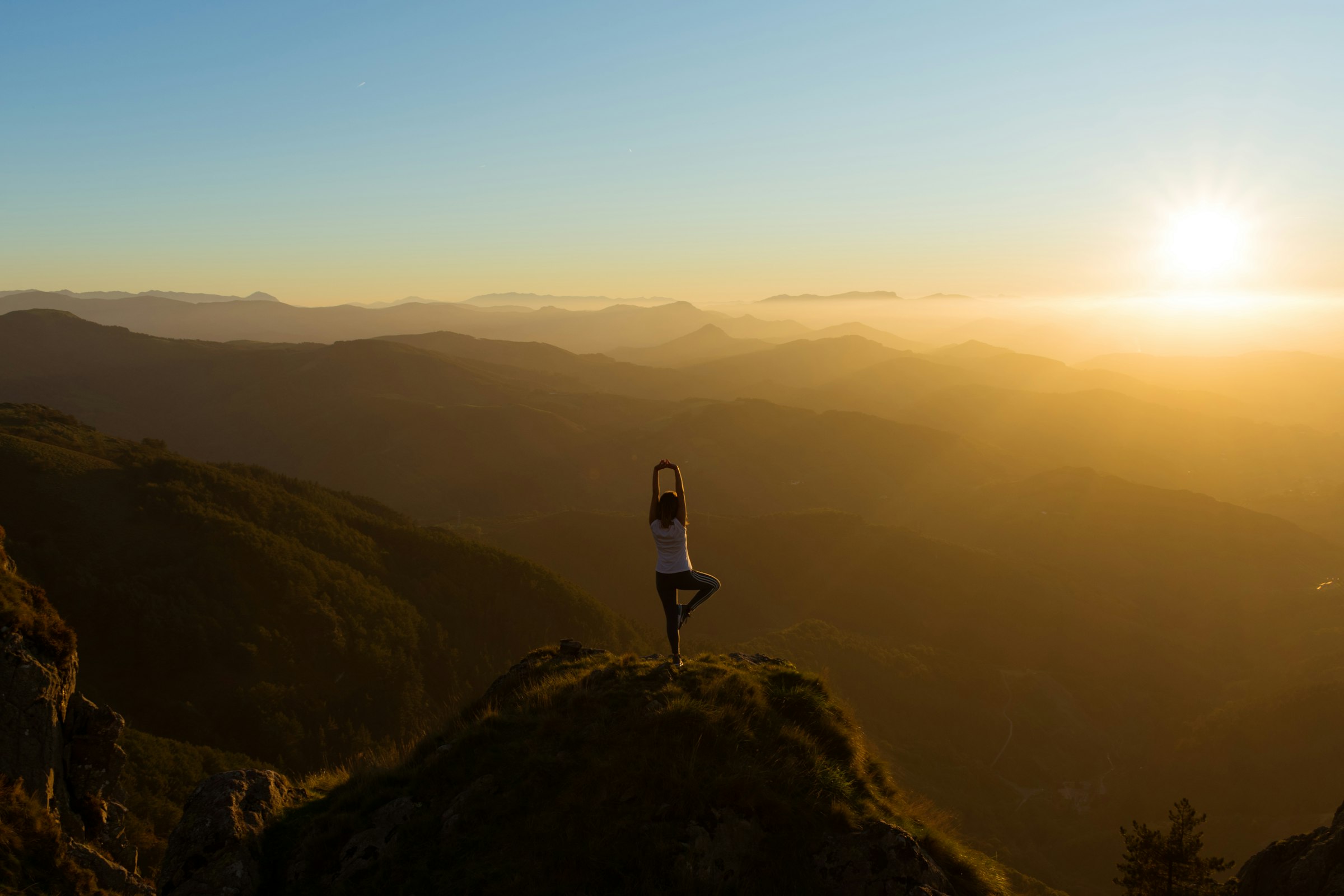 Woman stretching on a mountain top at sunrise